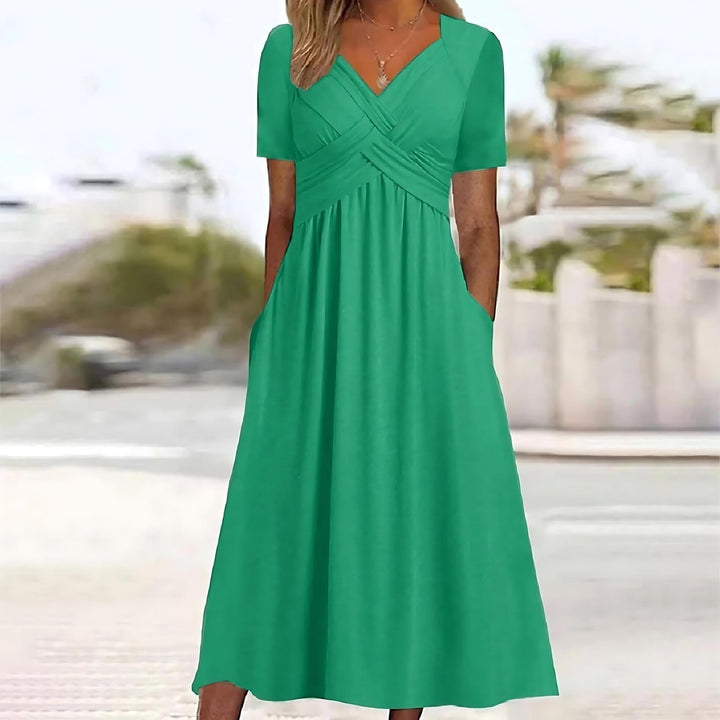 Woman wearing a midi dress with V-neckline on a plain background.
