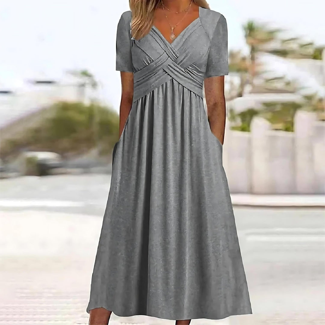 Woman wearing a relaxed fit midi dress with short sleeves on a plain background.