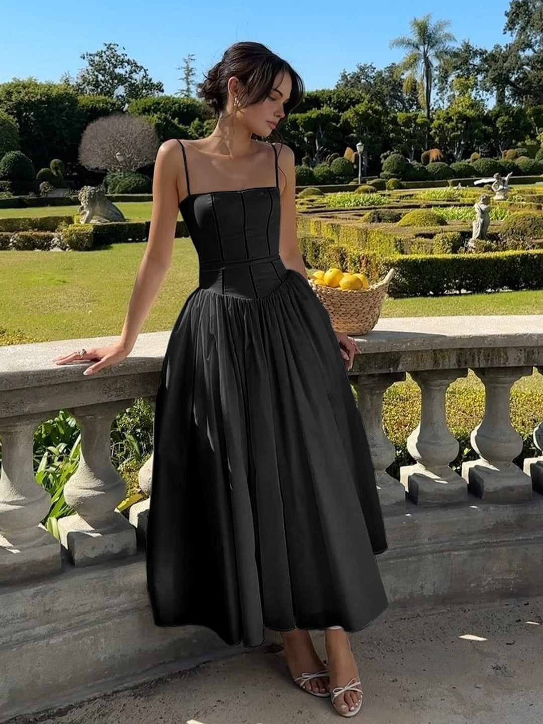 Female model in elegant summer dress walking through garden path.