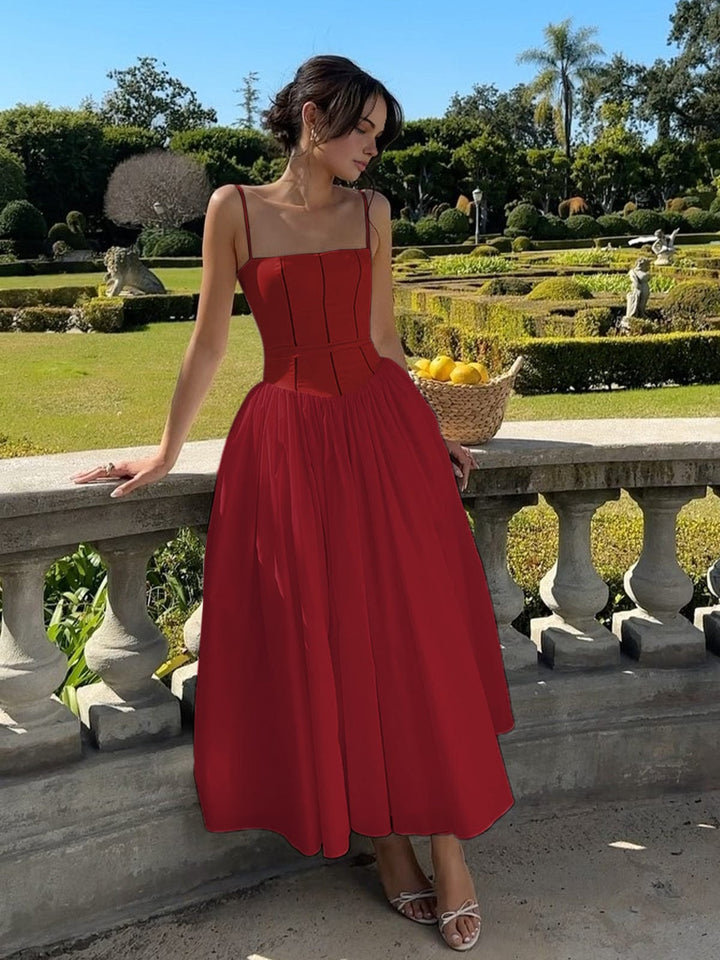 Woman in refined midi dress posing beside terrace railing.