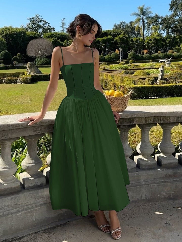 Female model wearing feminine occasion dress in lush nature setting.