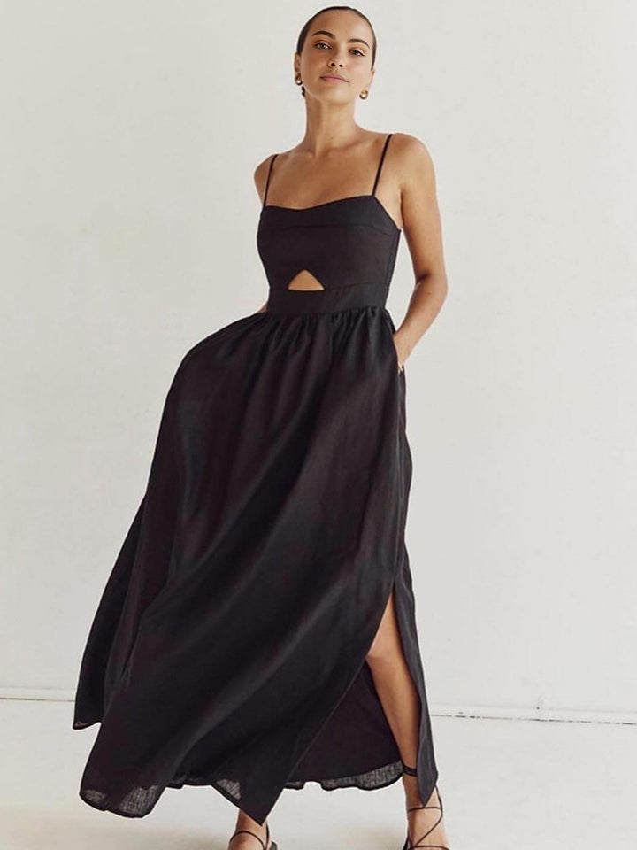 Woman showcasing a flowing sleeveless maxi dress with a graceful silhouette on a plain background.
