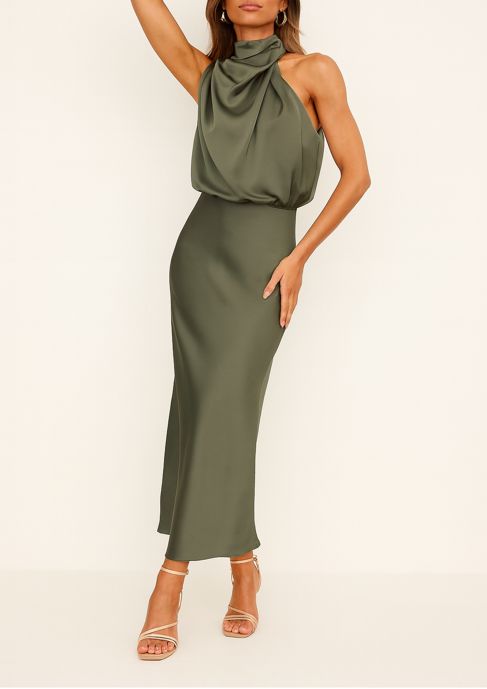 Woman posing in a draped midi dress with a flowing silhouette on a plain background.