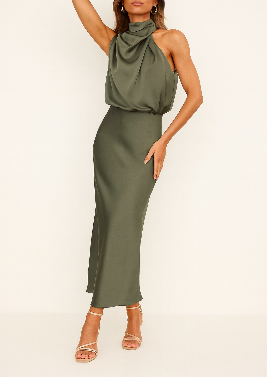 Woman posing in a draped midi dress with a flowing silhouette on a plain background.