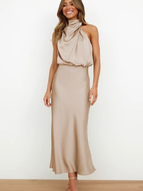 Woman posing in a fitted off shoulder evening dress on a plain background.