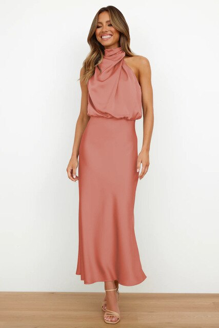 Female model in a graceful off shoulder cocktail dress on a plain background.