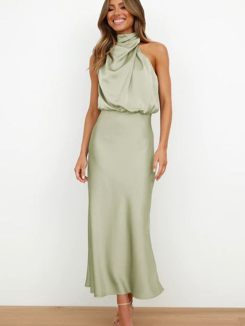 Woman wearing an off shoulder dress with a smooth flowing shape on a plain background.