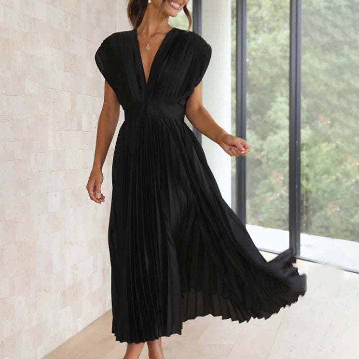 Woman in a sophisticated dress against a plain background.