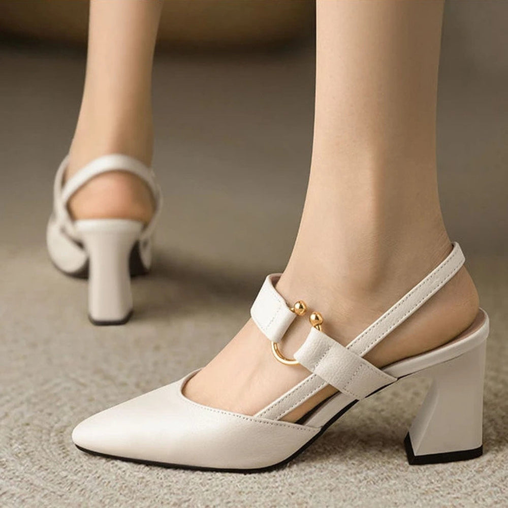  Woman showcasing stylish heeled sandals with a cushioned design on a plain background.