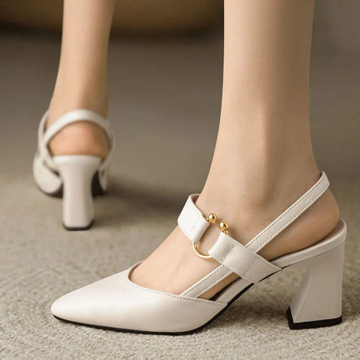  Woman showcasing stylish heeled sandals with a cushioned design on a plain background.
