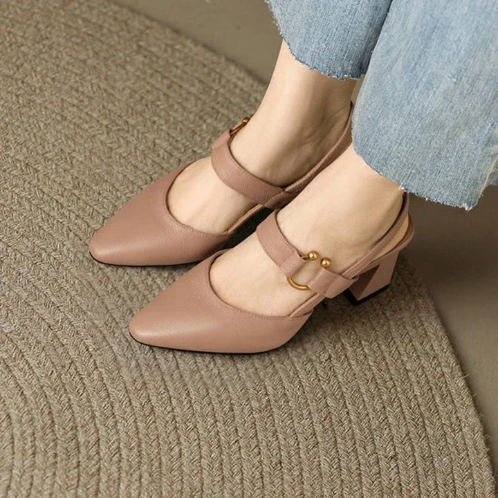 Female model presenting dressy heeled footwear on a plain background.