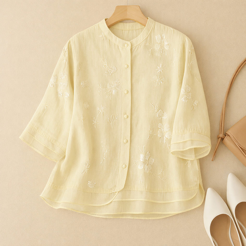 Stylish women’s embroidered top displayed on a plain backdrop.
