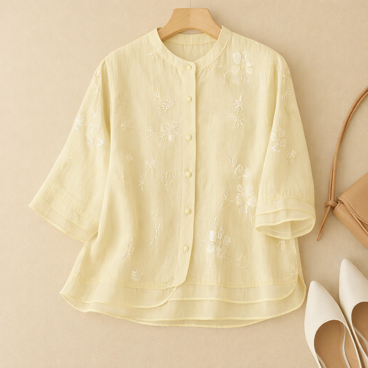 Stylish women’s embroidered top displayed on a plain backdrop.