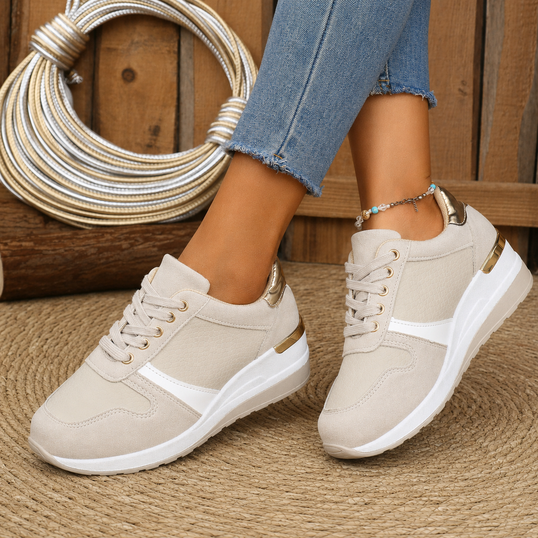 Close-up of female feet in breathable casual shoes on a plain backdrop.