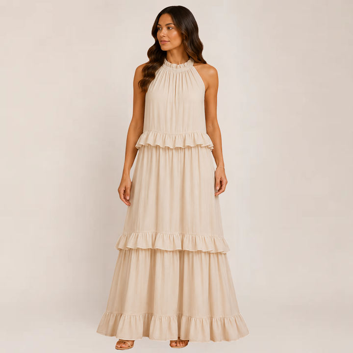 Female model showcasing a ruffle tiered dress with an airy silhouette on a plain background.