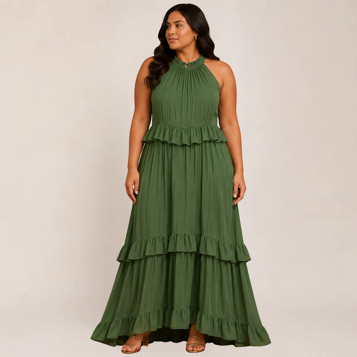 Woman wearing a flowy spaghetti strap maxi dress with cascading layers against a plain background.