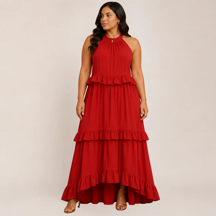 Female model wearing a flowy tiered maxi dress with spaghetti straps against a plain background.i 