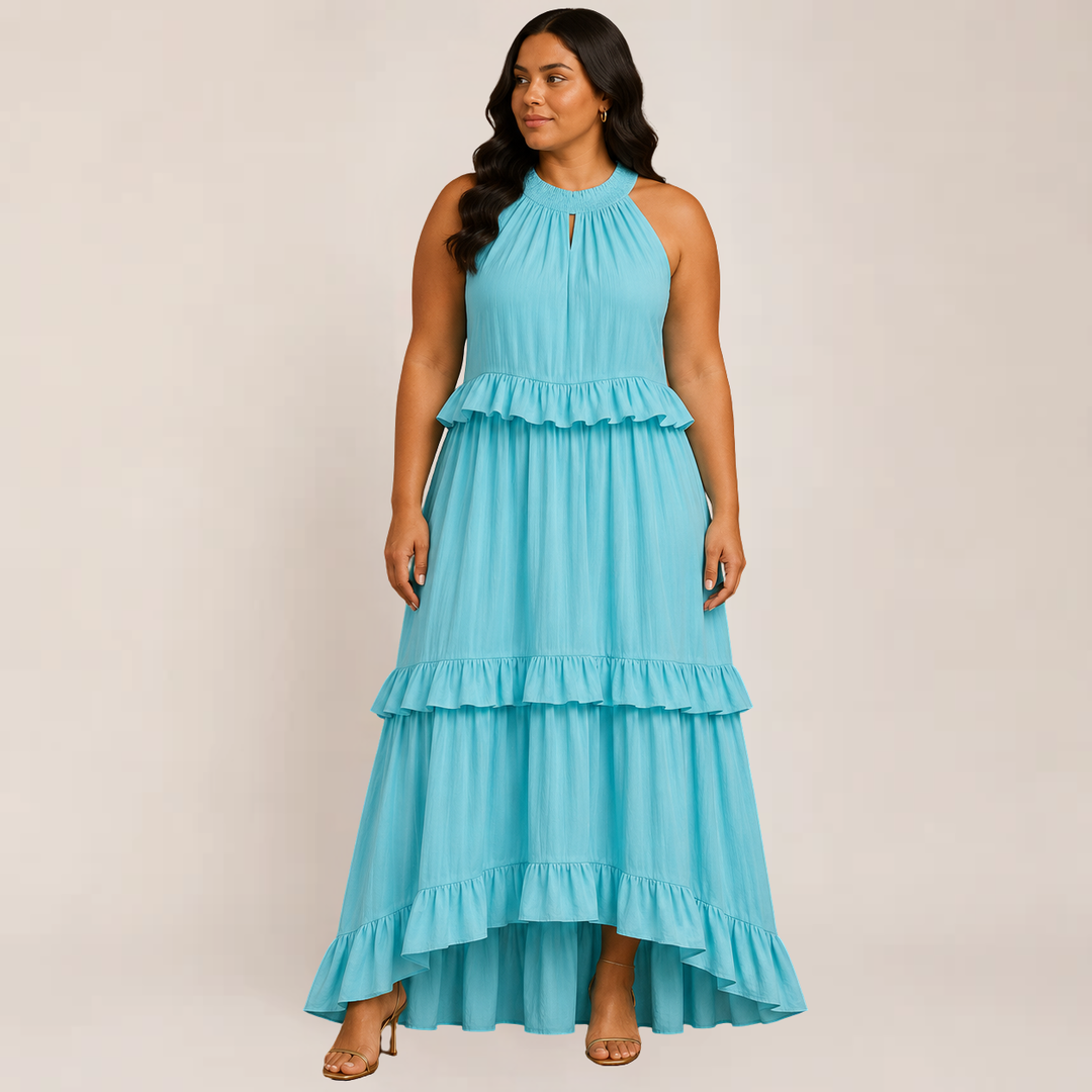 Female model posing in a sleeveless tiered summer dress with soft ruffle details on a plain background.