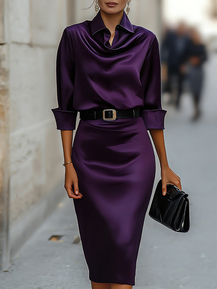 Female model in a draped collar midi dress with a defined waist on a plain background.