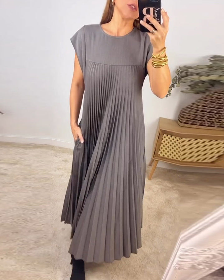 Female model wearing a flowing evening maxi dress with pleated detailing.
