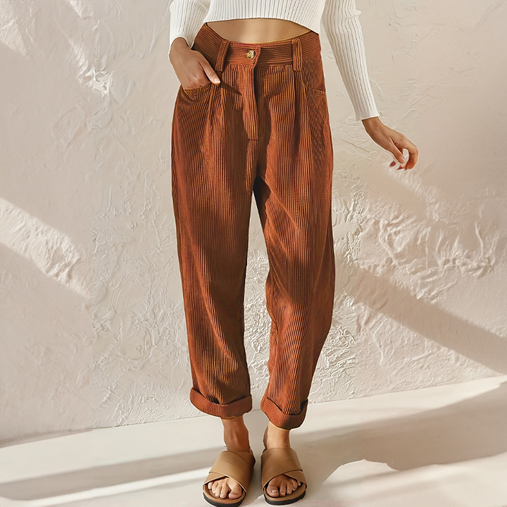 Female standing in casual tapered pants with side pockets against a plain background.