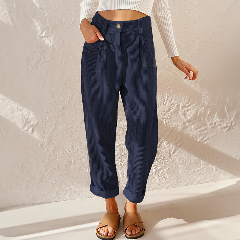 Female displaying relaxed leg corduroy pants with cuffed hems on a plain background.
