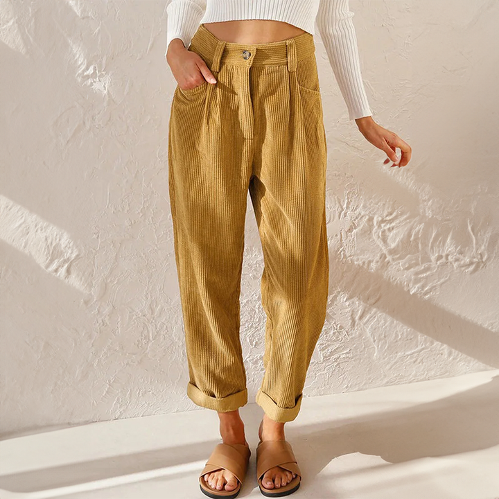 Woman wearing high waist corduroy trousers on a plain background.