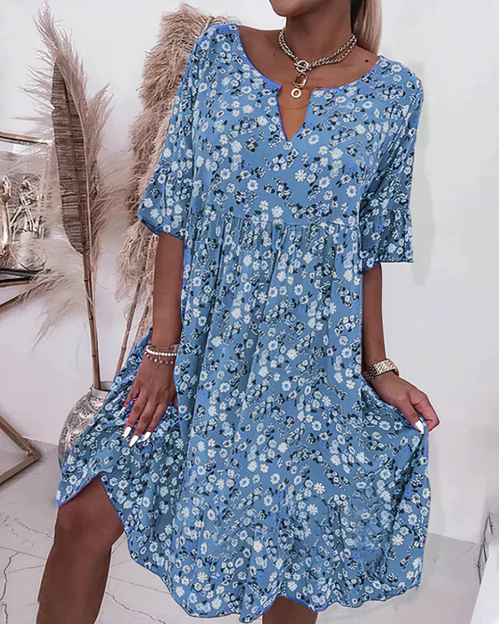 Woman posing in a cozy loose-fit dress with a clean plain backdrop.