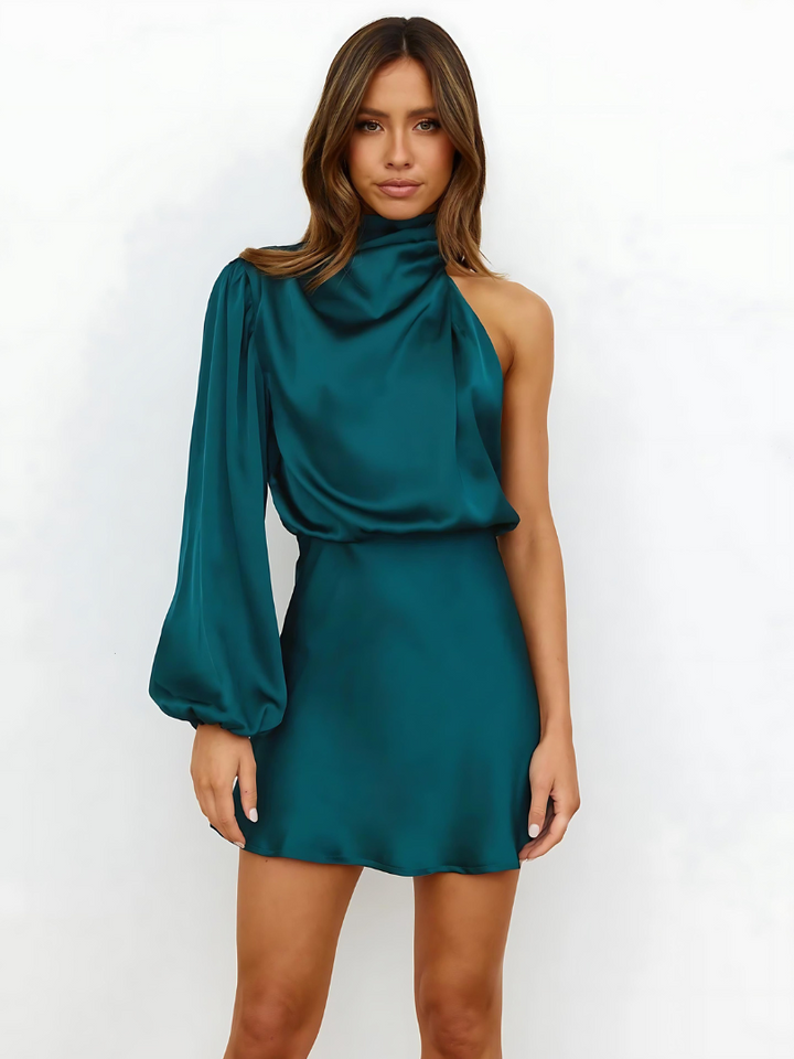 Female model in a chic short dress on a plain backdrop.