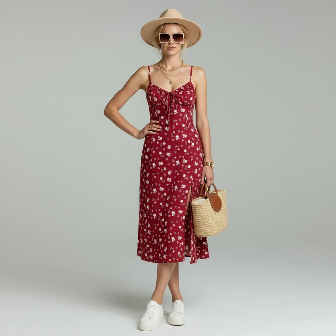 Female wearing a floral midi dress with spaghetti straps and a front slit against a plain background.