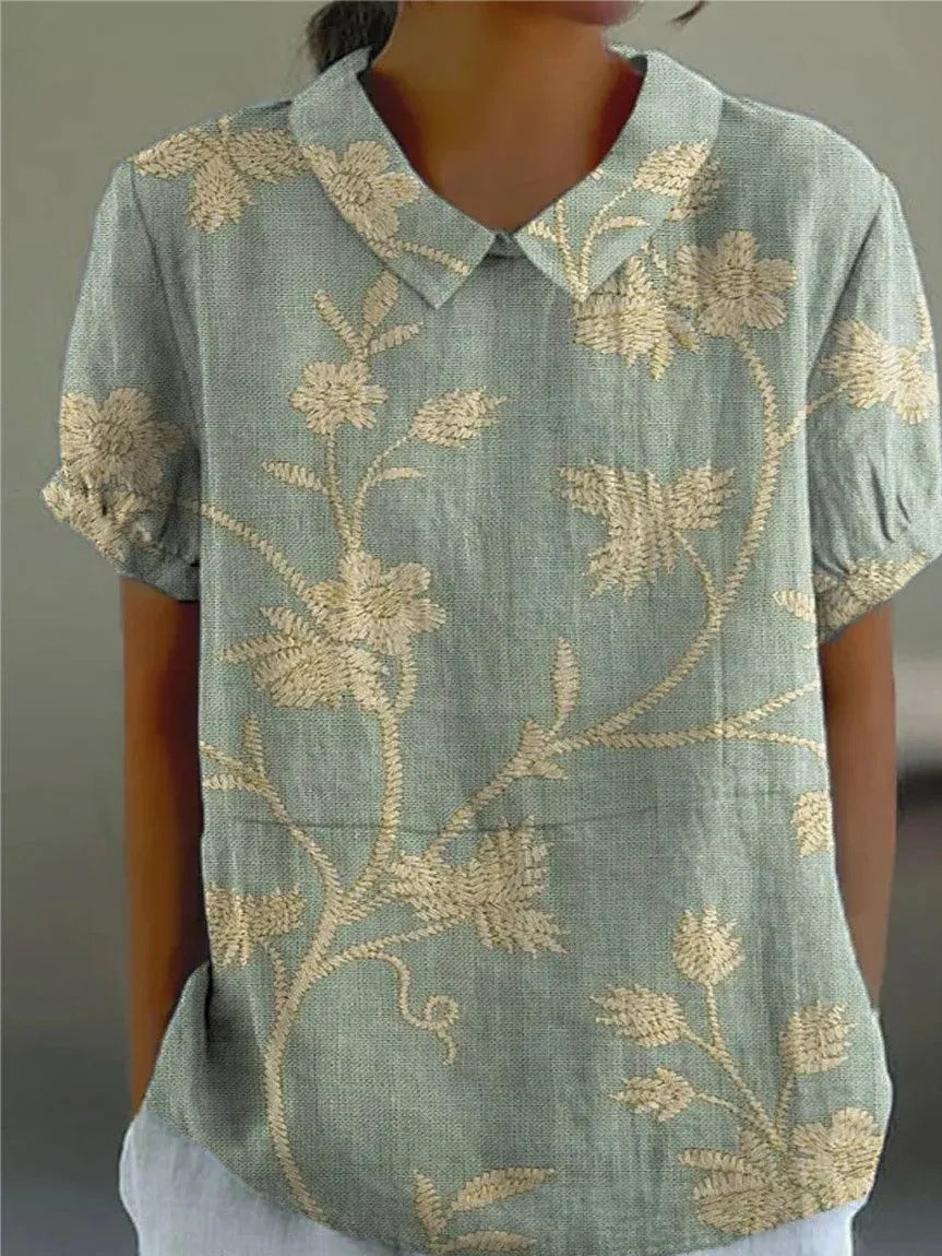 Floral women’s button-down shirt displayed on a person against a plain background.