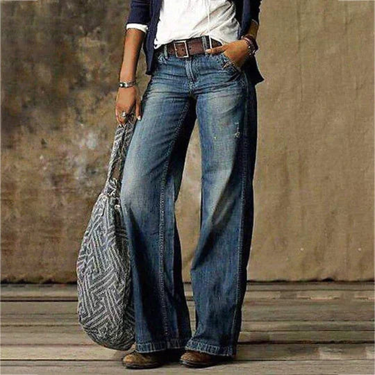 Female model in floor-length wide leg denim jeans on a clean background.