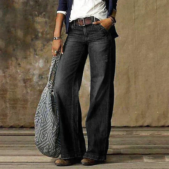 Female model wearing high rise wide leg jeans in a studio setting.