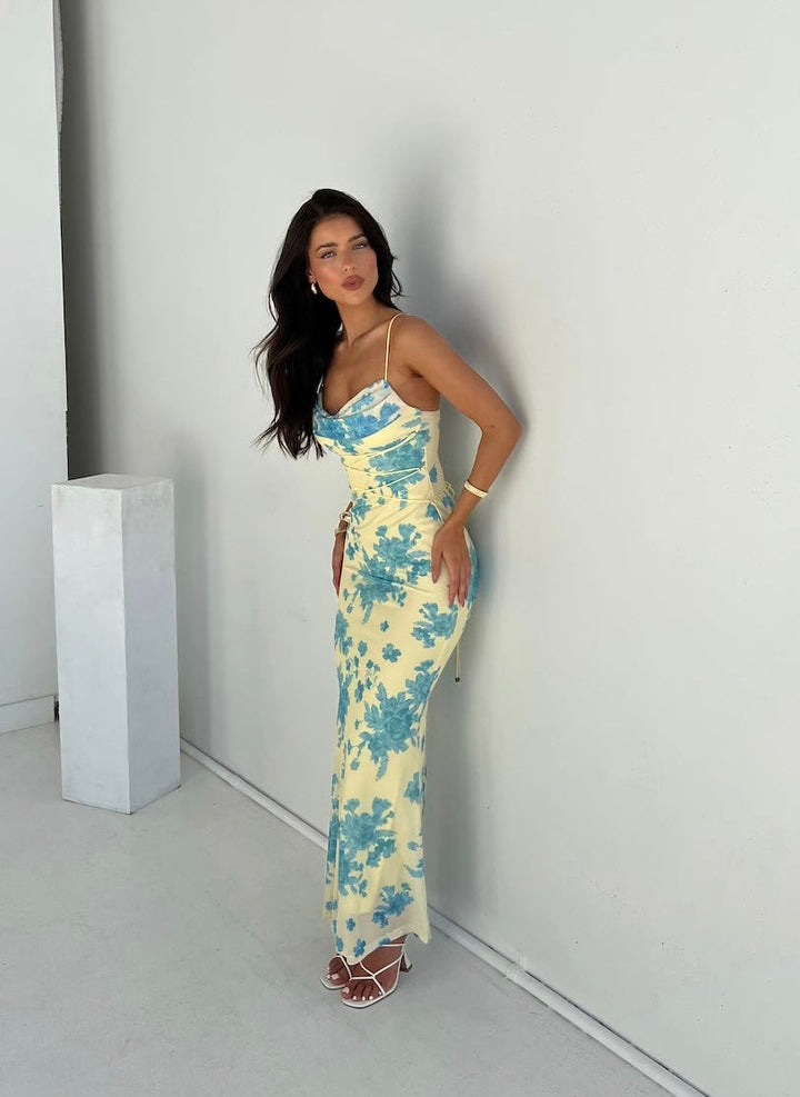 Woman wearing a floral maxi dress on a plain background.
