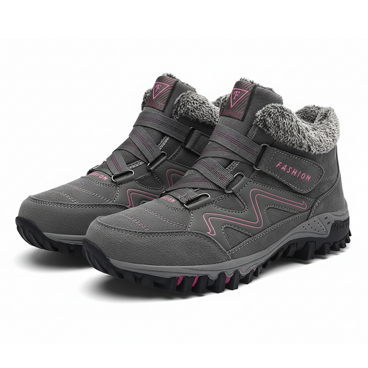 Close view of feet wearing stylish waterproof boots on a plain background.