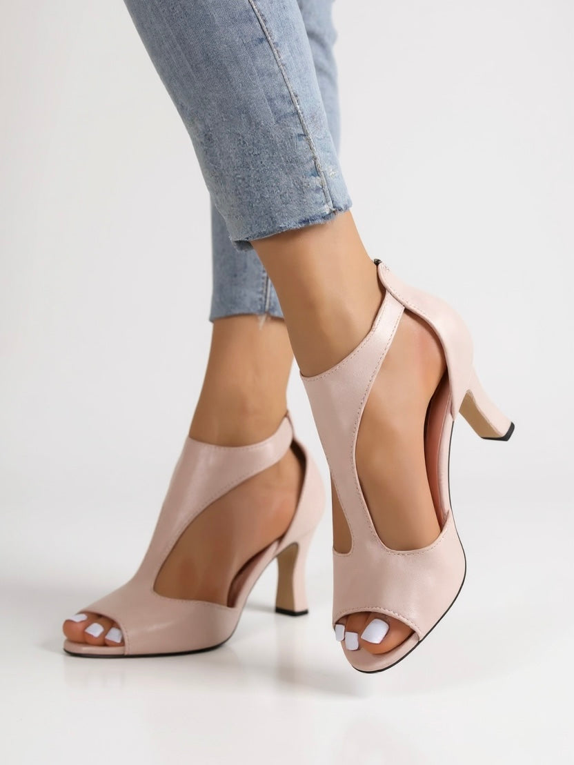 Female model standing in openwork block heel sandals on a plain backdrop.