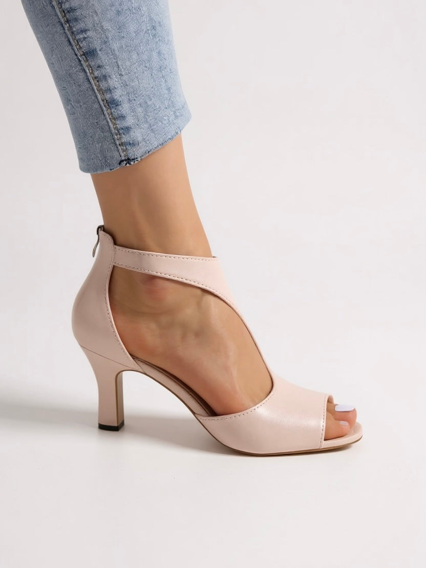 Woman wearing chic heeled sandals with cutout detailing on a plain background.