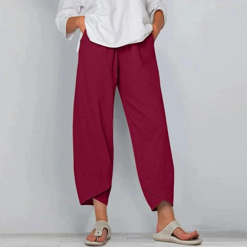 Woman wearing flowing summer pants with a refined casual look on a plain background.