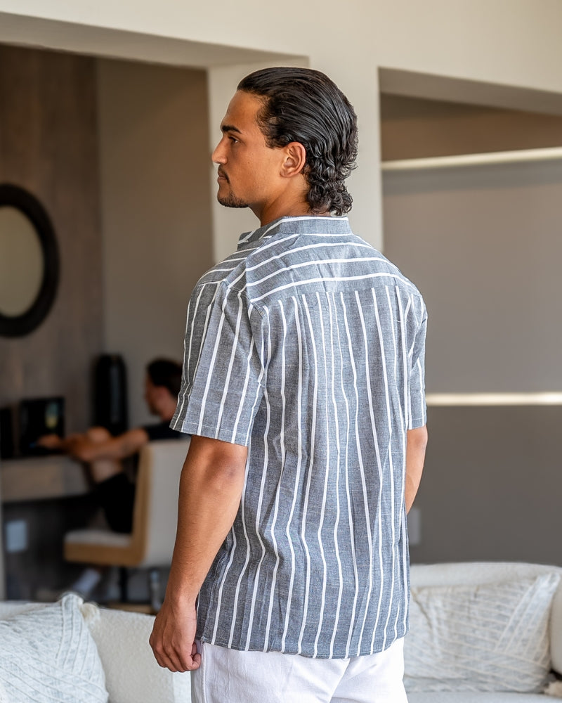  Man wearing a classic striped polo shirt styled with an open collar against a plain background.