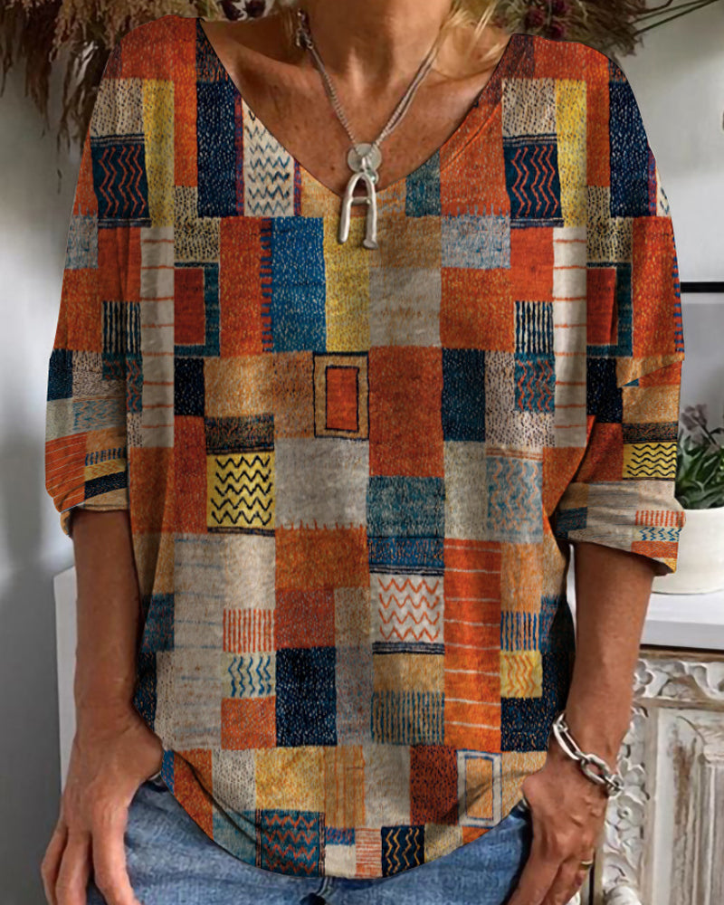 Female wearing a patchwork V-neck blouse with colorful geometric patterns on a plain background.