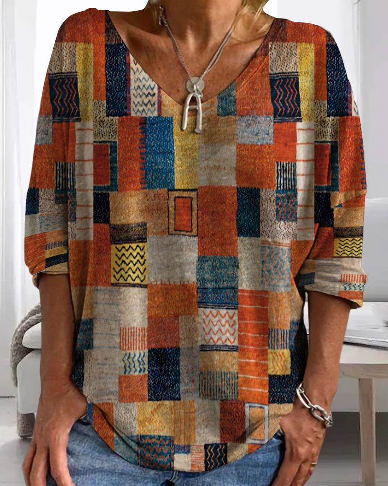  Woman modeling a vibrant geometric print blouse with 3/4 sleeves on a plain background.
