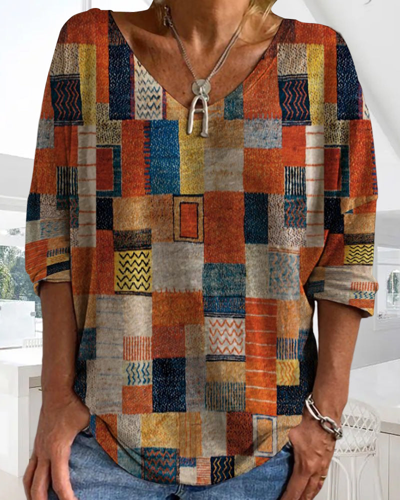  Female showcasing a colorful patchwork top with a flattering V-neck design on a plain background.