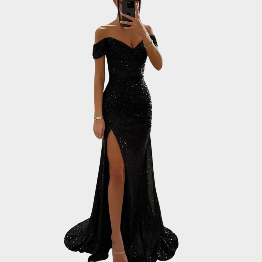 Woman in a fitted sparkling evening dress with open shoulder design on a plain background.