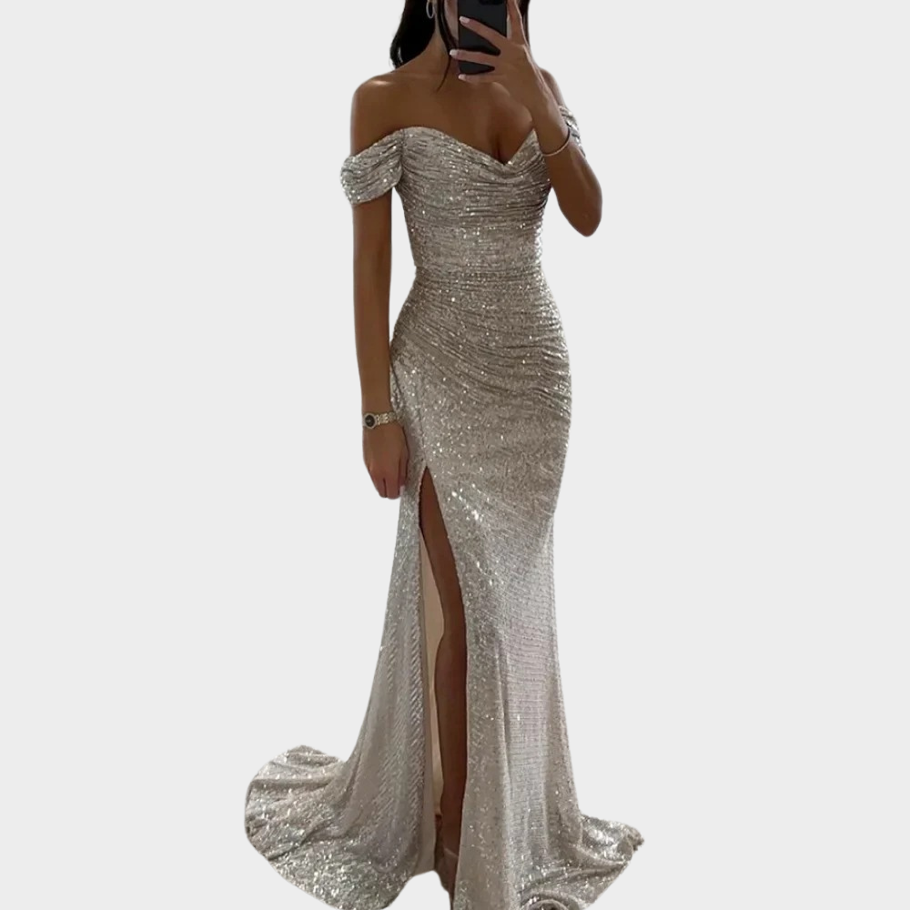 Female model in an open shoulder formal dress with fitted shape on a plain background.