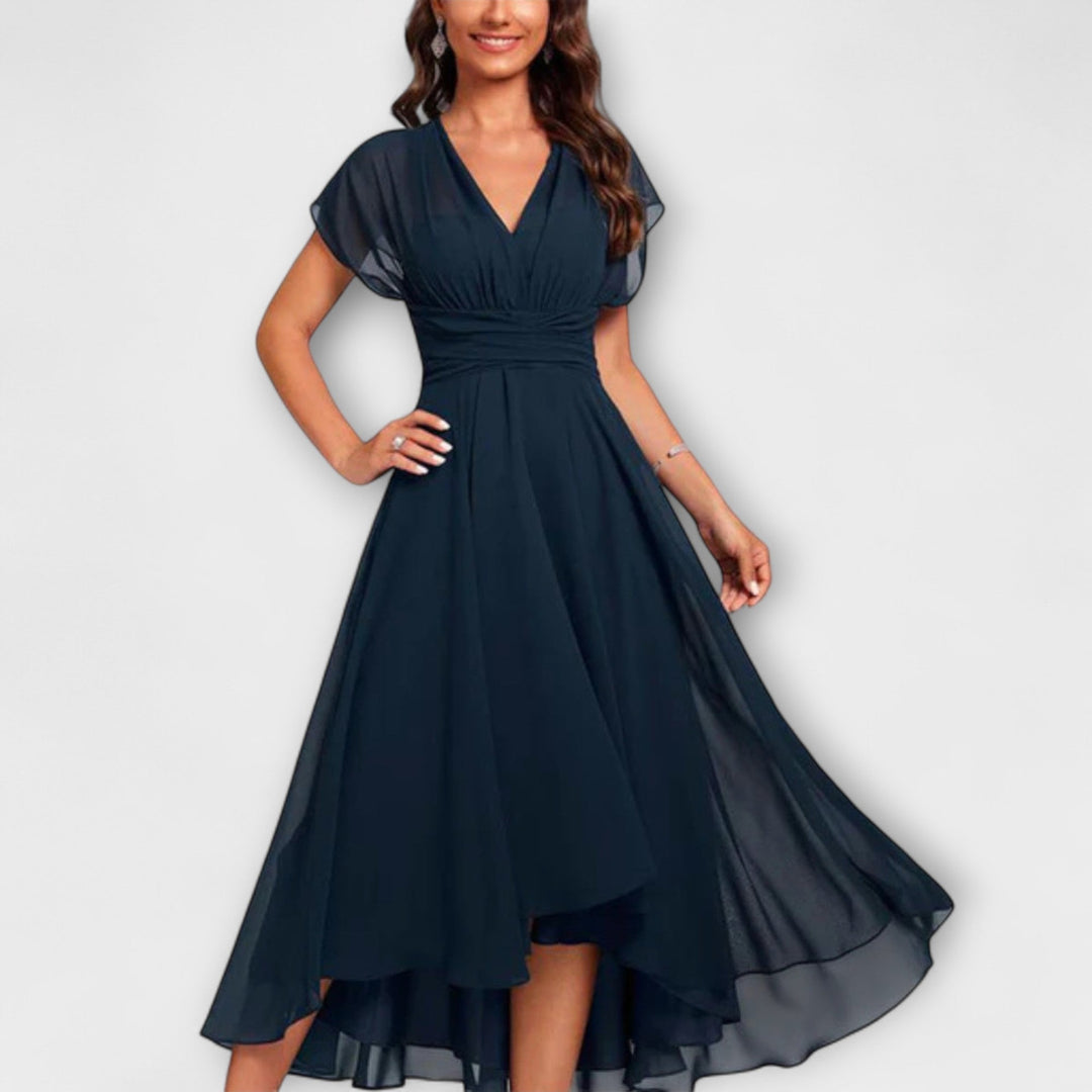 Woman wearing a V-neck flowing mini dress on a plain background.