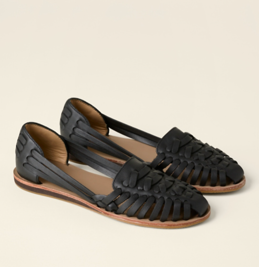 Female wearing woven ballet flats on a plain background.