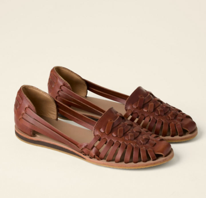  Woman showcasing braided slip-on flats against a plain background.