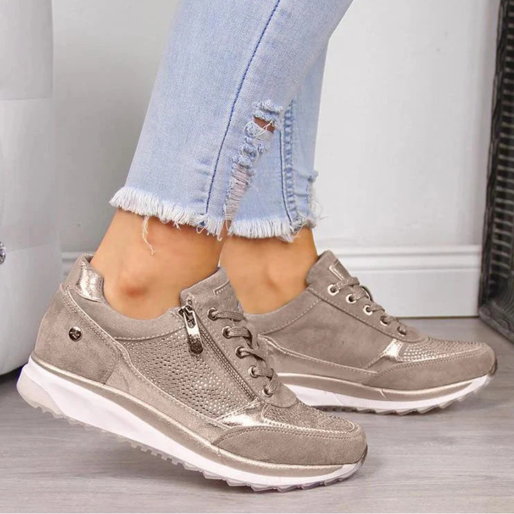 Female model showing comfortable walking shoes on a plain background.