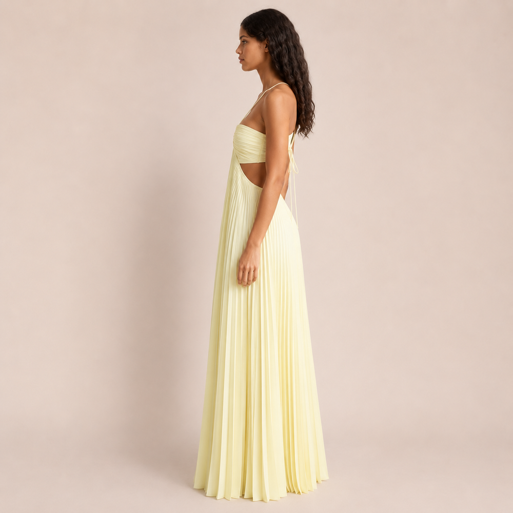 Woman posing in a flowing spaghetti strap evening dress against a plain background.