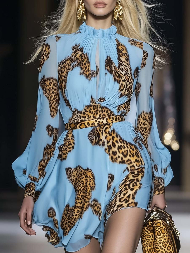 Woman posing in a flowing animal print mini dress with ruffle neckline on a plain background.